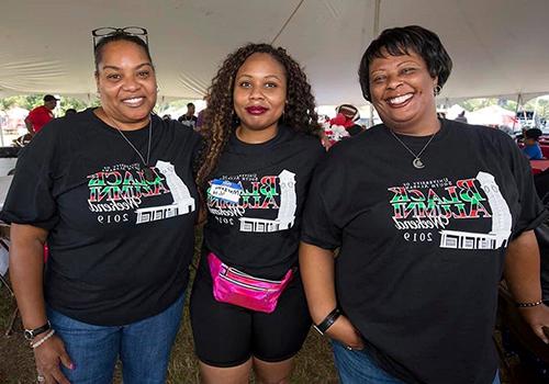 Three members of the Black Alumni Society under the tent at the Black Alumni Weekend.